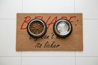 Beware: Dog Can’t Hold Its Licker coir doormat with pet bowls on top
