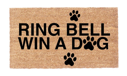 Close-up of Ring Bell Win a Dog coir doormat showing black lettering and paw print details
