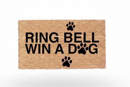 Ring Bell Win a Dog coir doormat with black lettering and paw print design on natural coconut fiber